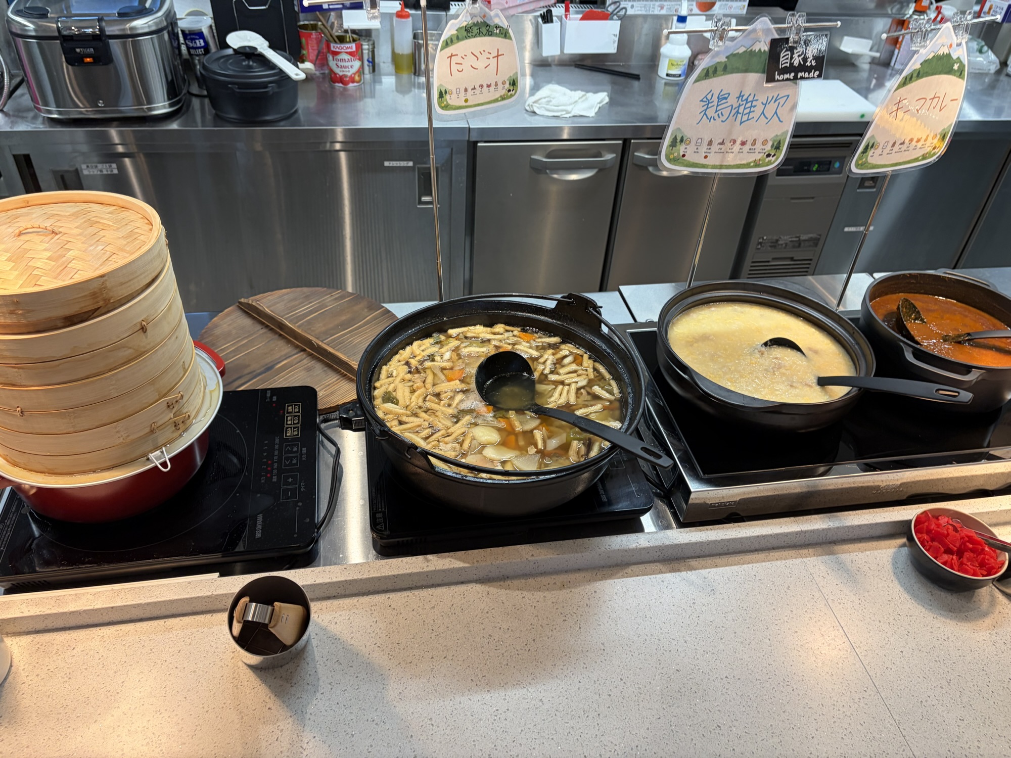 たびのホテル阿蘇熊本空港の朝食。中央の大きな鍋には具だくさんの「だご汁」があり、隣には鶏雑炊やキーマカレー、せいろ料理も並ぶ、郷土色豊かなビュッフェコーナー。