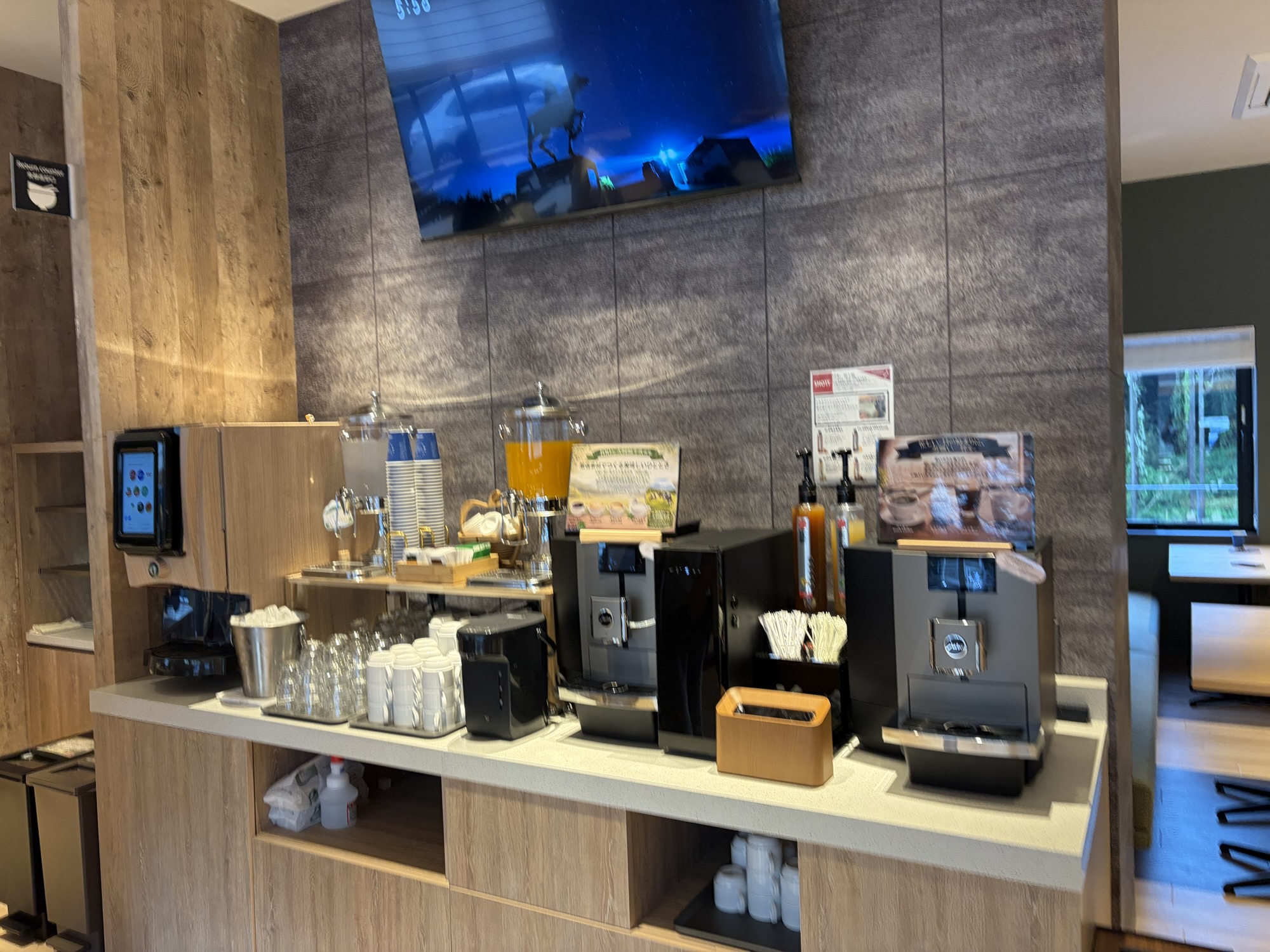 たびのホテル阿蘇熊本空港の朝食ビュッフェのドリンクコーナー。本格的なコーヒーマシンやジュースサーバー、カップ類が綺麗に並んでいます。
