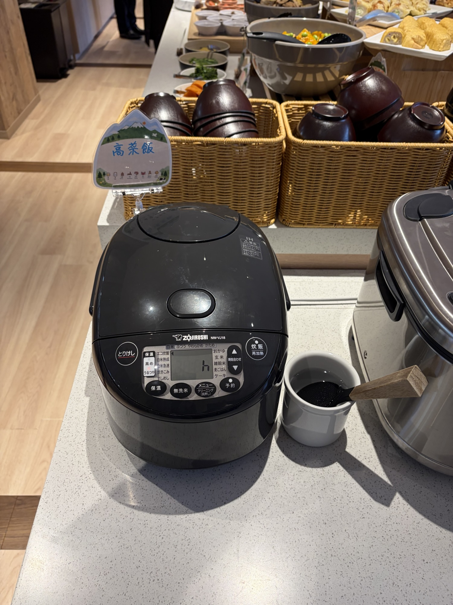 たびのホテル阿蘇熊本空港の朝食ビュッフェ。熊本名物「高菜飯」の可愛い案内札が立てられた炊飯器が置かれており、ご当地ならではの朝ごはんを楽しめます。