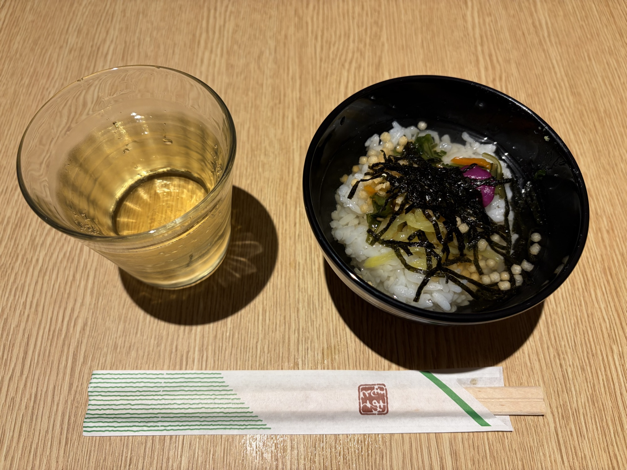 たびのホテル阿蘇熊本空港の夜食「だし茶漬け」とウェルカムドリンク。海苔やあられをたっぷり乗せたお茶漬けと、グラスに入った飲み物です。