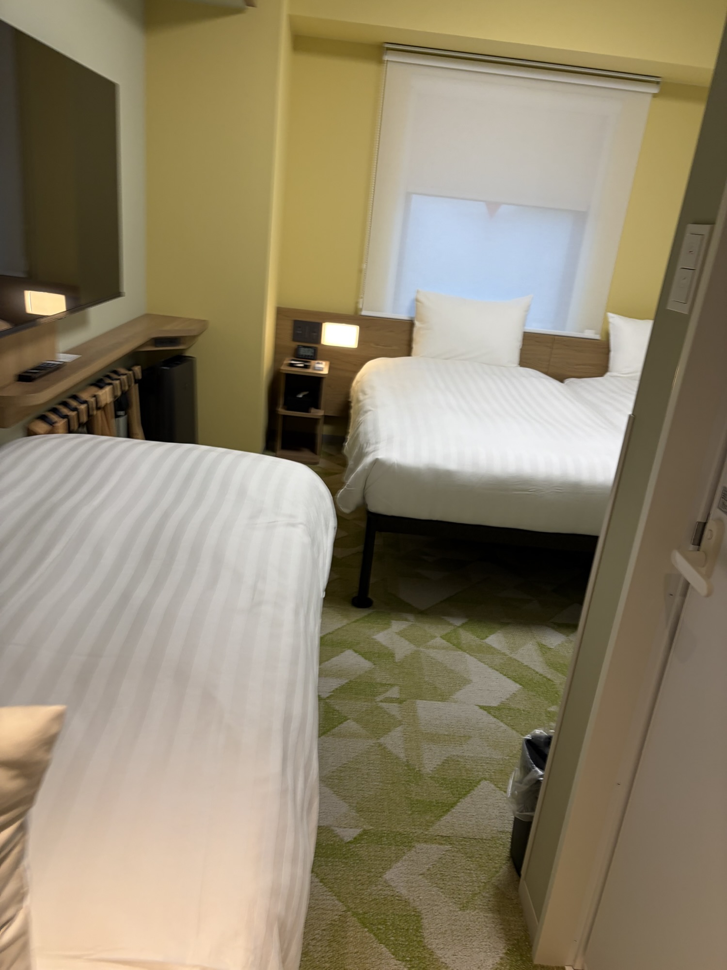 たびのホテル阿蘇熊本空港のツイン＋エキストラベッド（20㎡）の室内。入口から見た様子で、壁掛けの大型TVとベッド3台が並び、やや手狭な空間です。