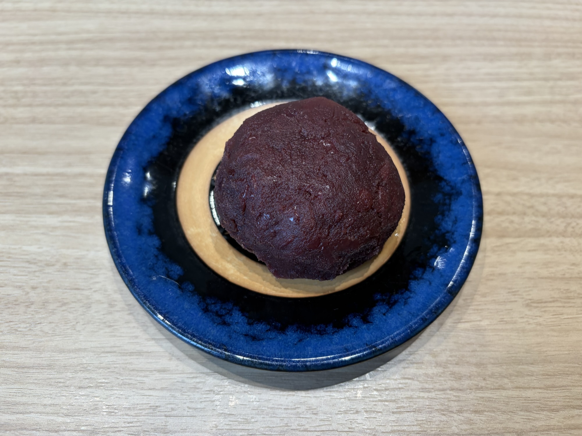 青い皿に盛り付けられた資さんうどん名物のぼた餅。程よい甘さのあんで包まれた手作り和菓子