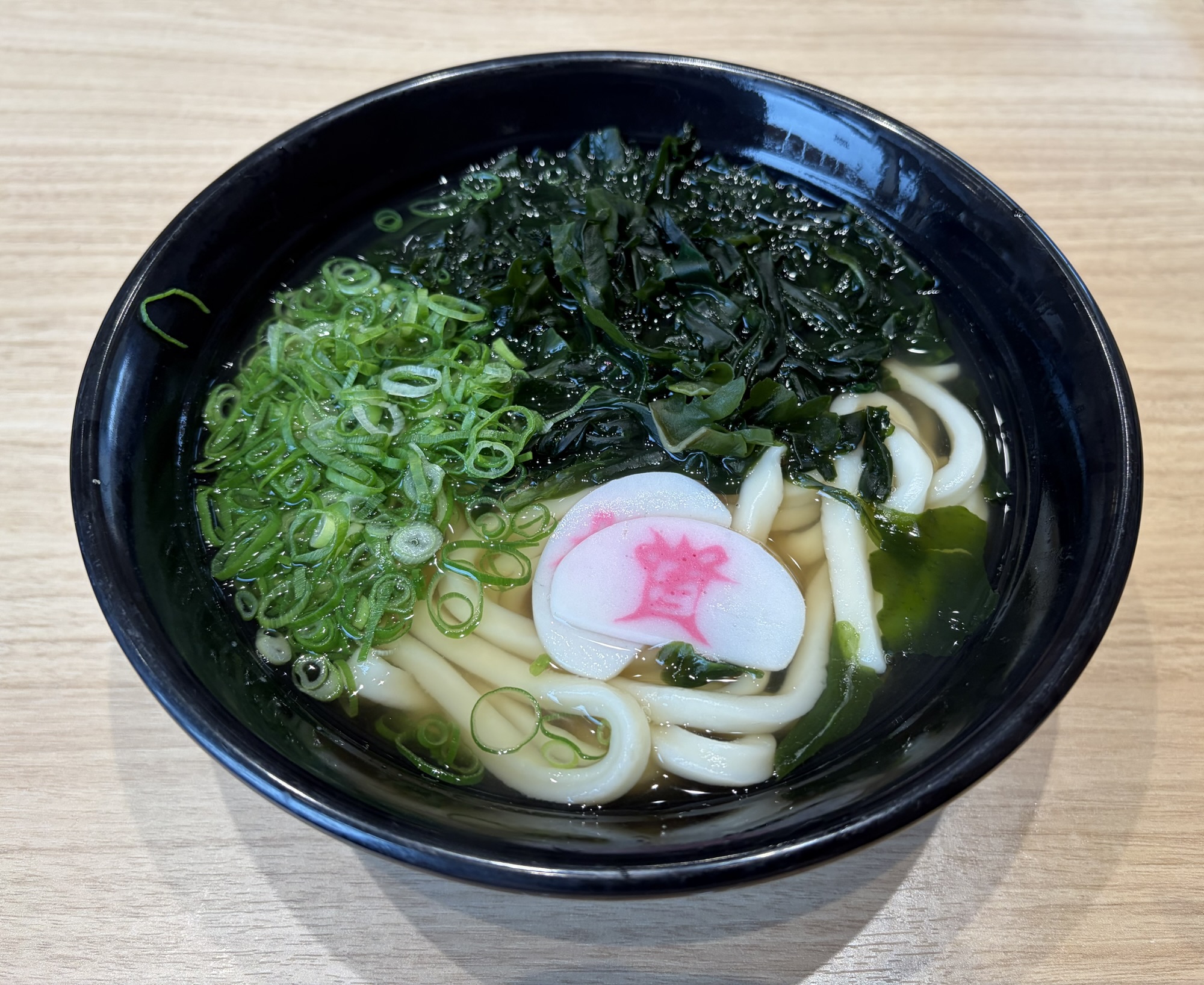 資さんうどんの子ども用に注文したわかめうどん。たっぷりのわかめとネギ、資のロゴ入りかまぼこが乗った一杯